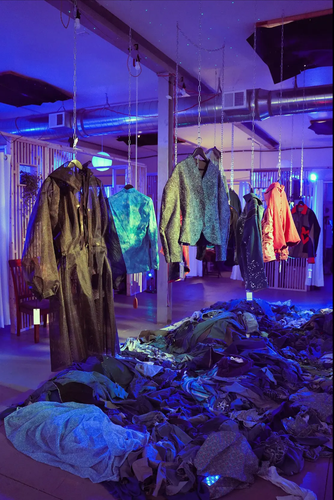 One-of-a-kind jackets suspended above reclaimed textiles at Slow Stitch's Collective Power showcase